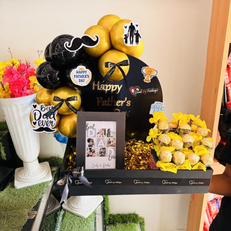 Golden Moments for Dad Hamper featuring a personalized photo frame, Ferrero Rocher chocolate bouquet, black and gold chrome balloons, and Fathers Day decorations by Send My Feelings.
