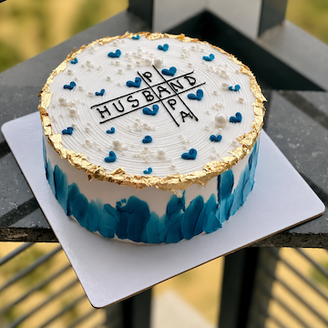 Our Superman Celebration Cake featuring a 1/2 kg butterscotch cake with husband and papa theme, blue heart decorations and elegant gold detailing by Send My Feelings.